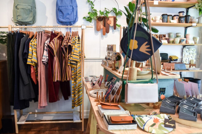 Image of a fashion store with clothes on display backpacks on the wall.